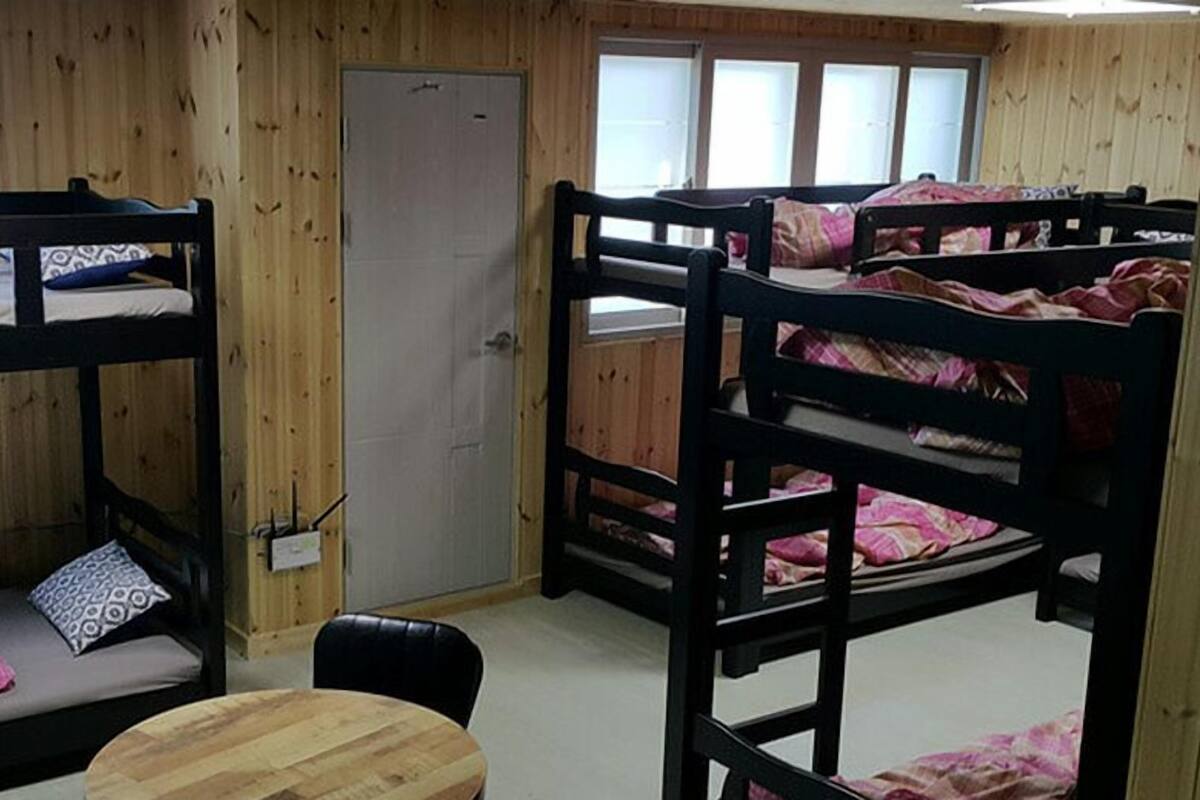 Ein Schlafsaalzimmer mit Etagenbetten, einer Holztür und einem kleinen runden Tisch.