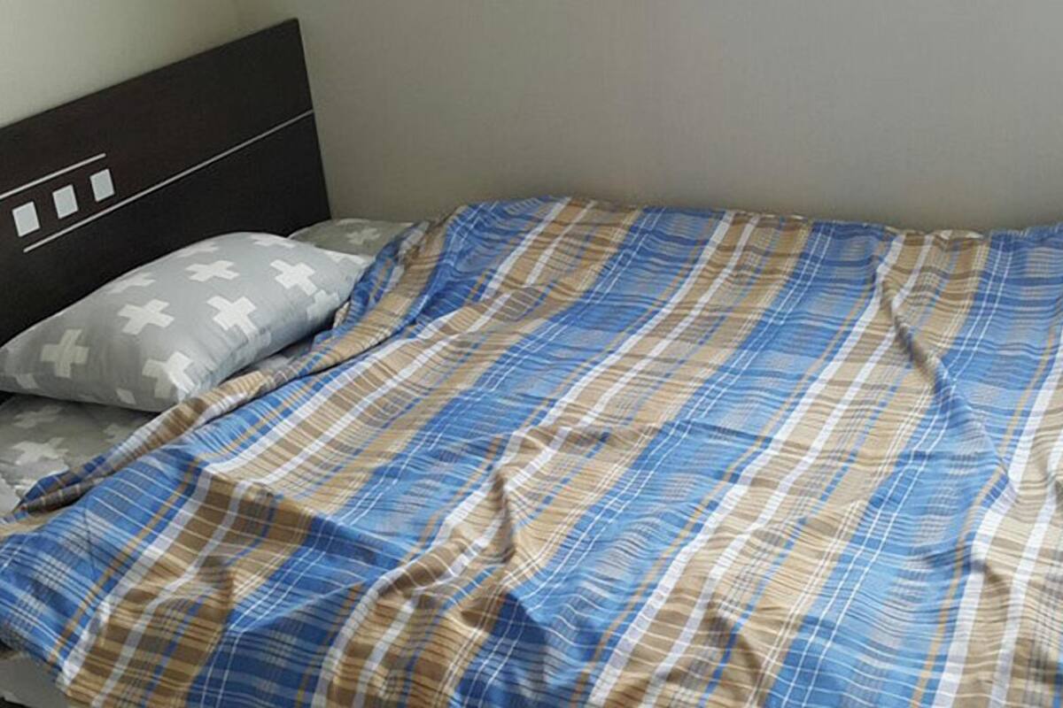 Ein Bett mit einer karierten Tagesdecke und einem Kopfkissen mit Kreuzmuster.