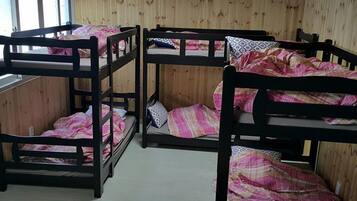 Ein Zimmer mit drei Etagenbetten, Holzwänden und einem Fenster.
