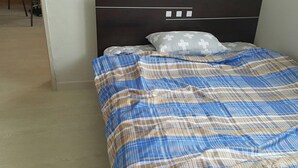 A bed with a plaid bedspread and a cross-patterned pillow.