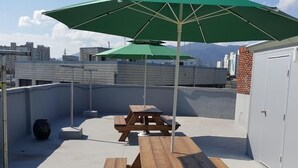 A rooftop patio with picnic tables and a green umbrella.