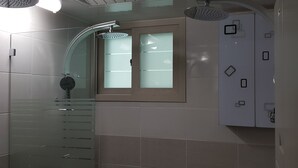 A modern bathroom with a curved shower, frosted glass window, and a frosted glass door.