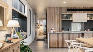 Una cocina moderna con detalles de madera, una isla central y taburetes blancos.