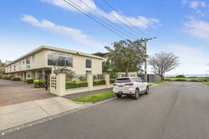 A residential building with a gated entrance, a driveway, and a parked car.