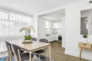 A modern kitchen with white cabinets, a built-in oven, and a window. - Brighton By Sea with sea glimpses (Brighton)