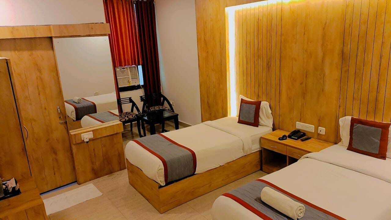 A hotel room with two beds, a desk, a chair, a mirror, and a wardrobe.