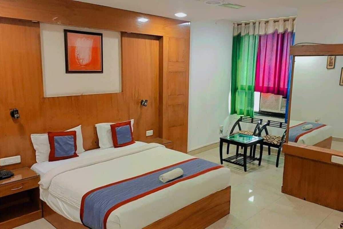 A hotel room with a wooden bed, bedside tables, a desk, and a chair.