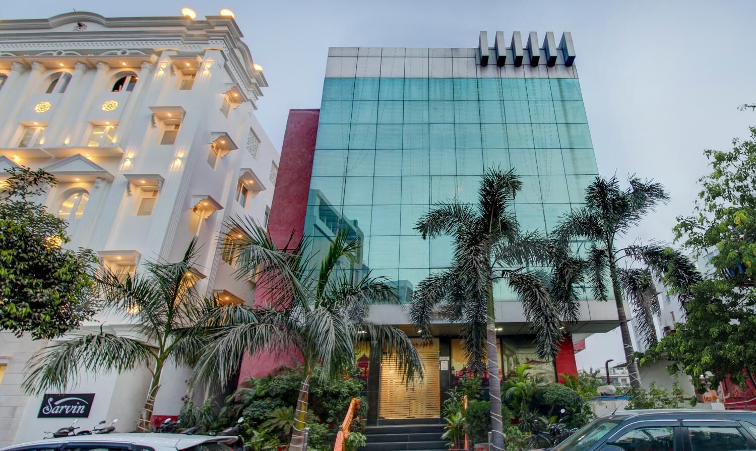A modern building with a glass facade and a traditional building with ornate detailing.