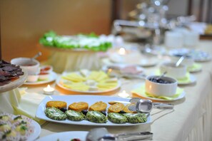 A buffet table with various food items and serving utensils. - Hotel Gold (Skopje)