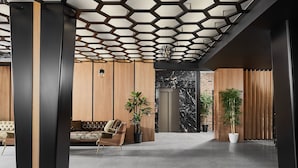 A modern lobby with a geometric ceiling, a plush sofa, and potted plants. - Hotel Gold (Skopje)