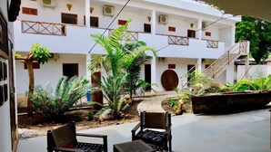 A courtyard with a white building, outdoor seating, and a boat named "The African Mariner". - 27 Cafe Zanzibar Airport Hotel (Zanzibar Town)