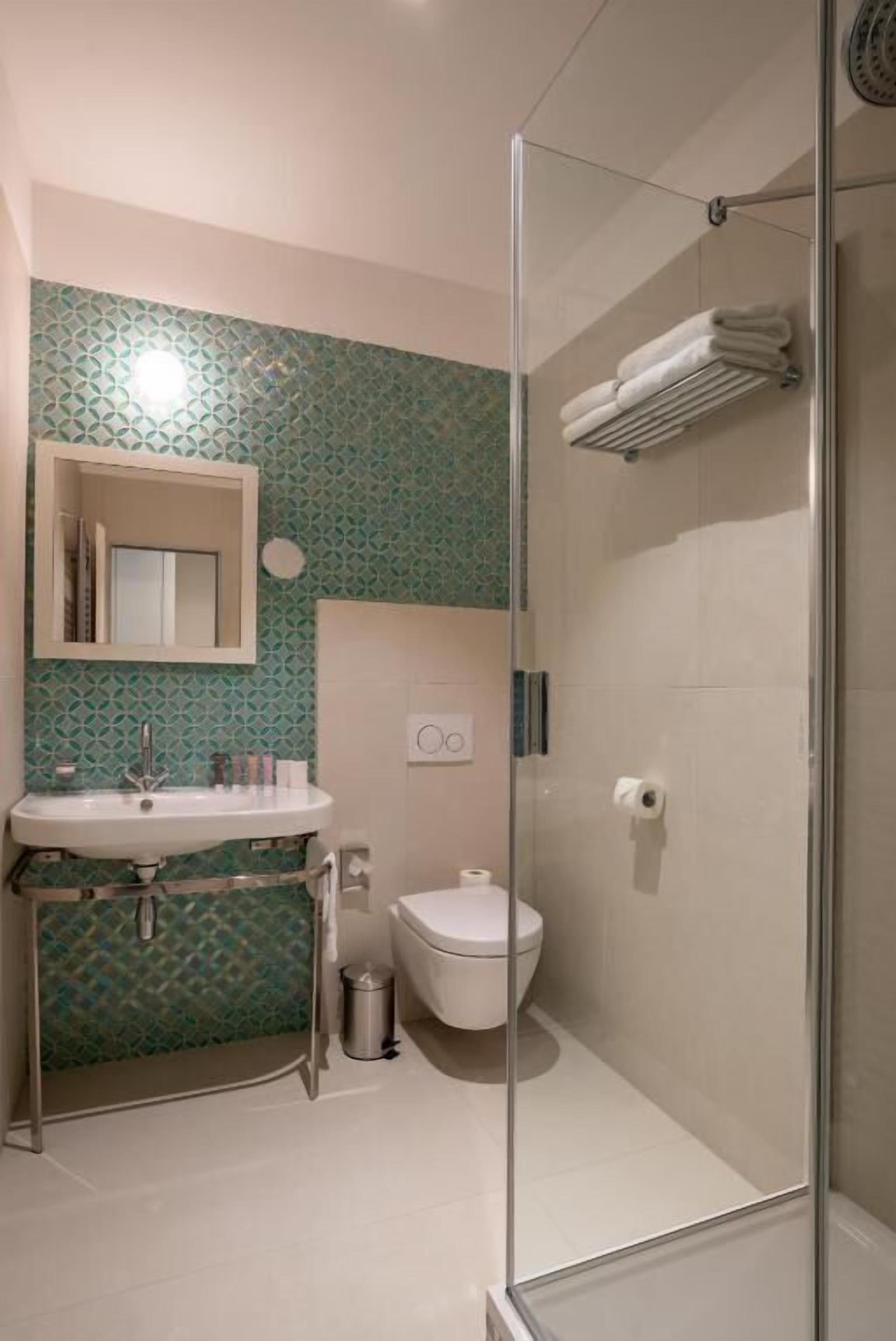A bathroom with a glass-enclosed shower, a sink with a mirror, and a toilet.