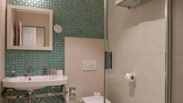 A bathroom with a glass-enclosed shower, a sink with a mirror, and a toilet.
