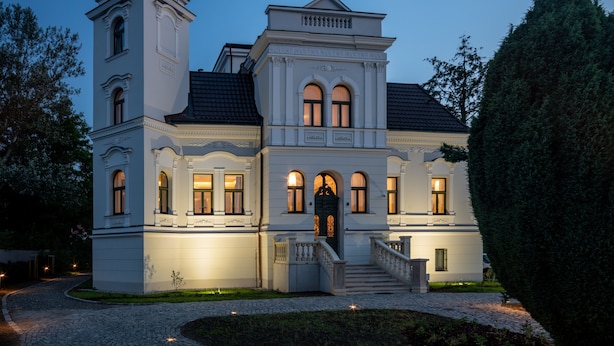 Ein großes, weißes Gebäude mit einem markanten Turm und einem zentralen Eingang mit Stufen.