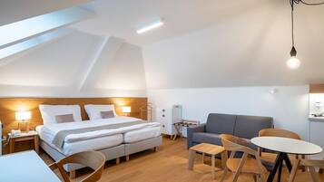 Quarto moderno e bem iluminado, com uma cama grande, um sofá, uma mesa de jantar e uma pequena cozinha.