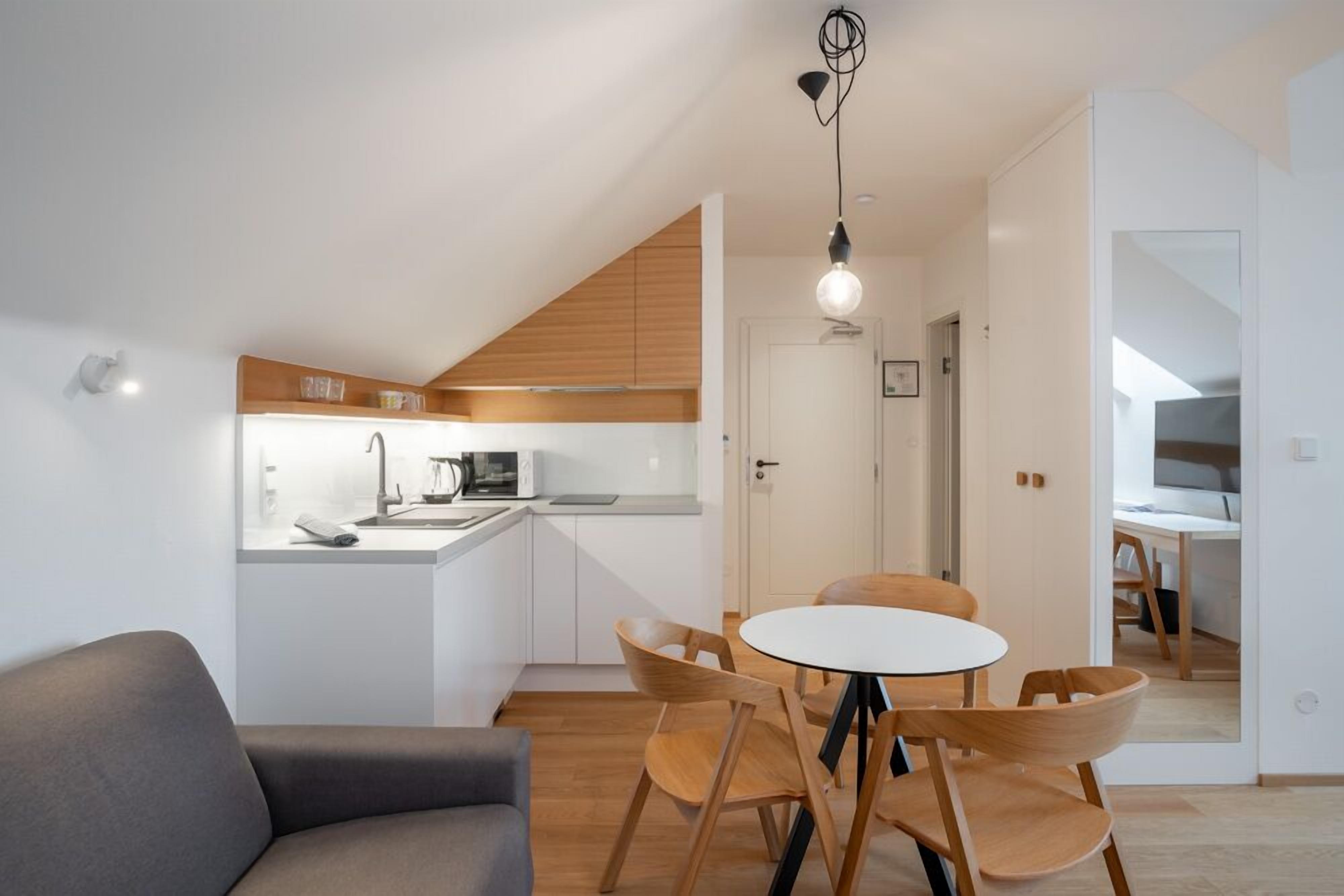 Una cocina moderna con armarios blancos, encimera de madera y un comedor con una mesa redonda y sillas de madera.