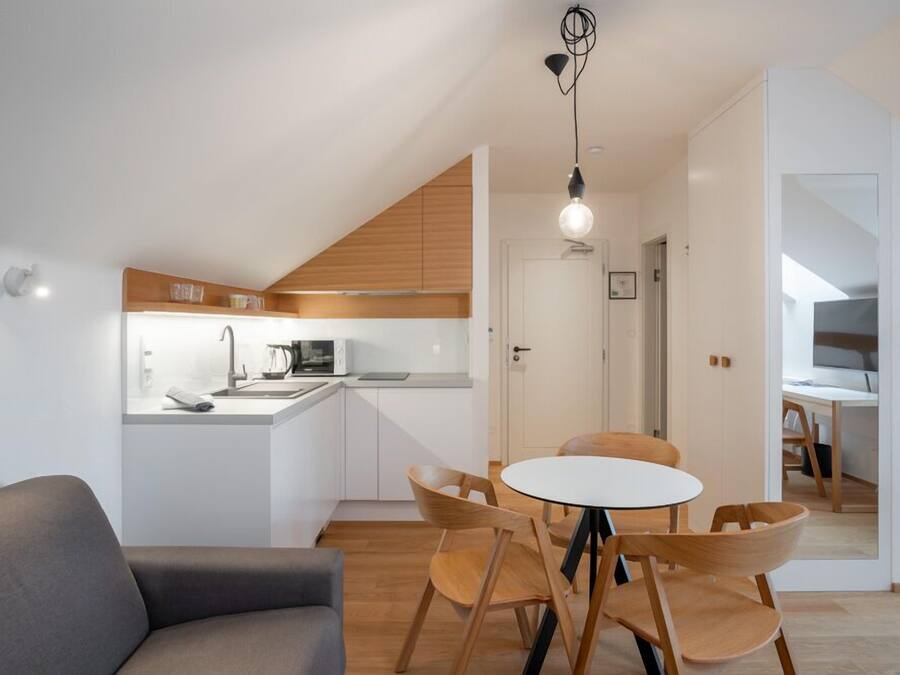 A modern kitchen with white cabinets, a wooden countertop, and a dining area with a round table and wooden chairs.