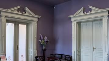 Una habitación con un techo decorativo, dos puertas blancas, un banco y una pequeña mesa con un florero.