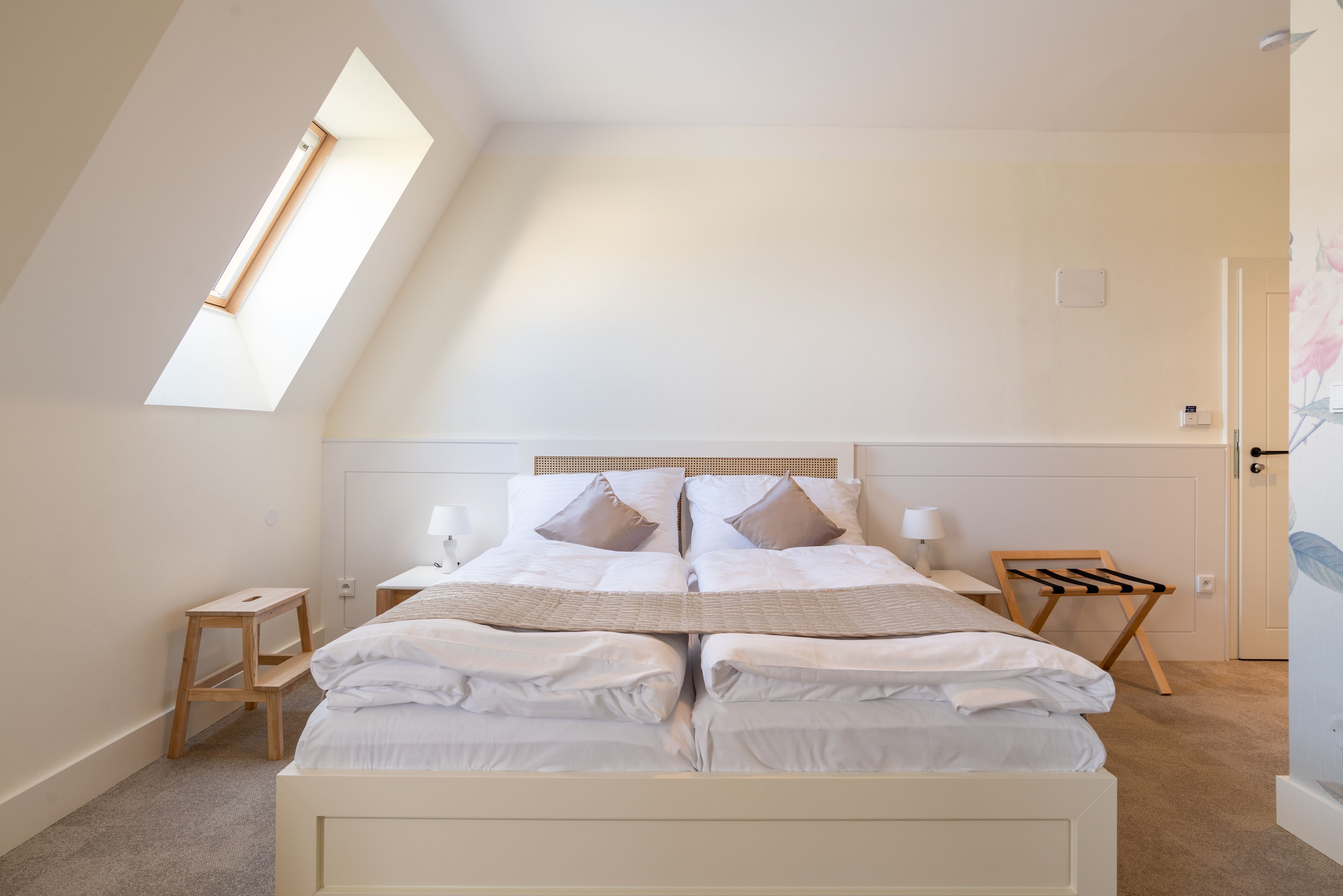 A bedroom with a large bed, a skylight, a bedside table, and a nightstand.