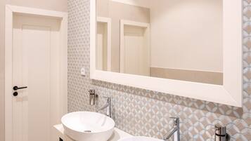 Un baño moderno con dos lavamanos, un espejo grande y azulejos con diseño.