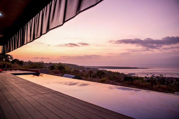 A wooden deck with a pool overlooking a coastal landscape during sunset. - The Arancia Villa (Penida Island)