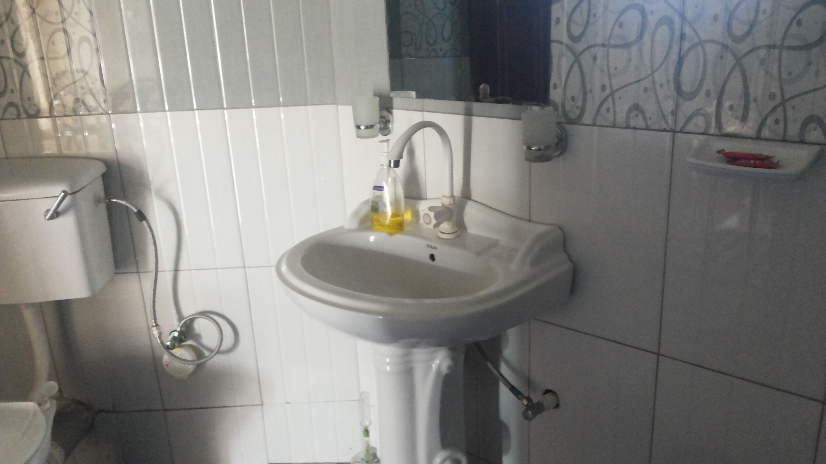 Een badkamer met een wit wastafel, toilet en spiegel.
