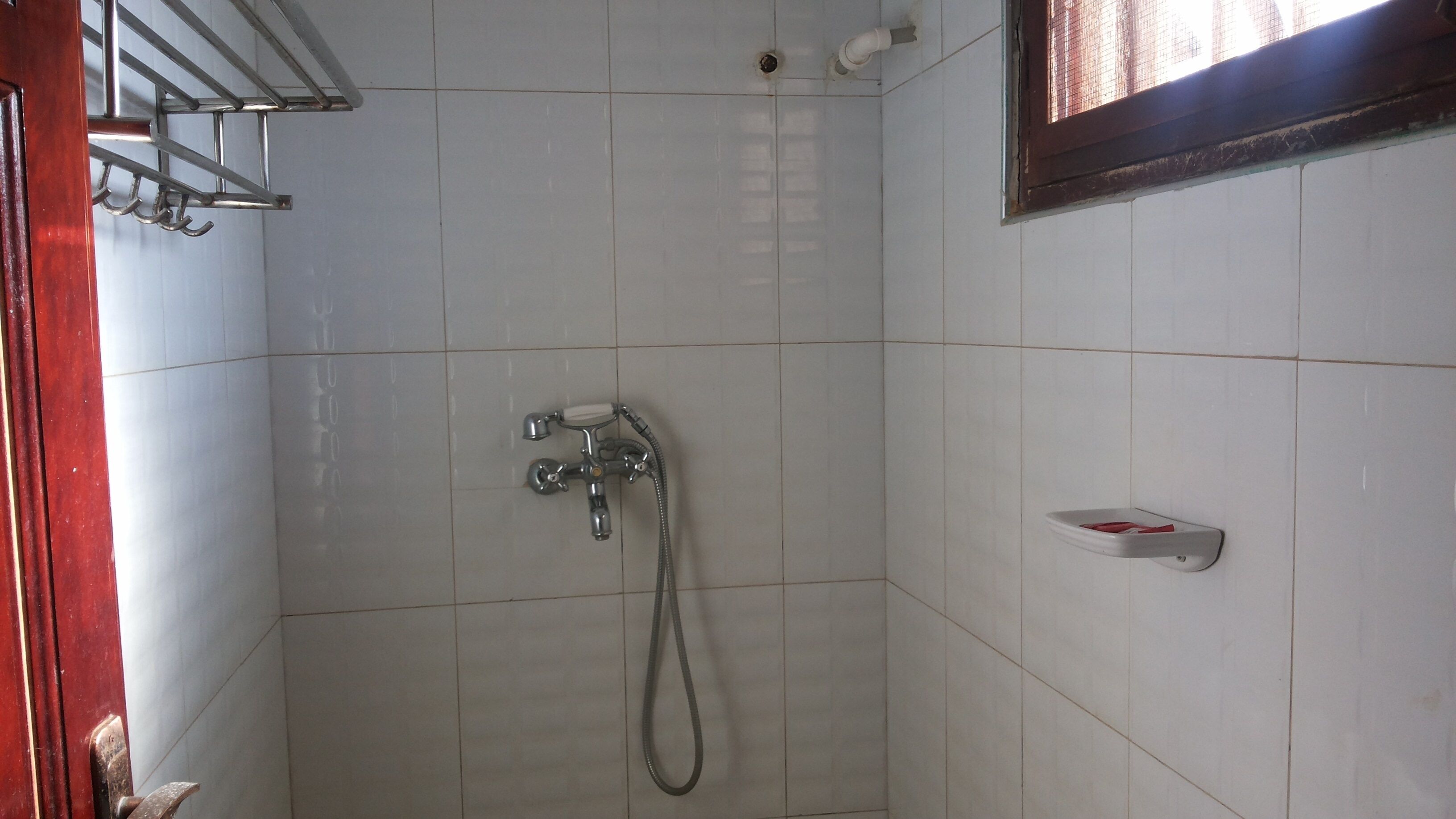A small, tiled shower area with a handheld showerhead and a wall-mounted faucet.