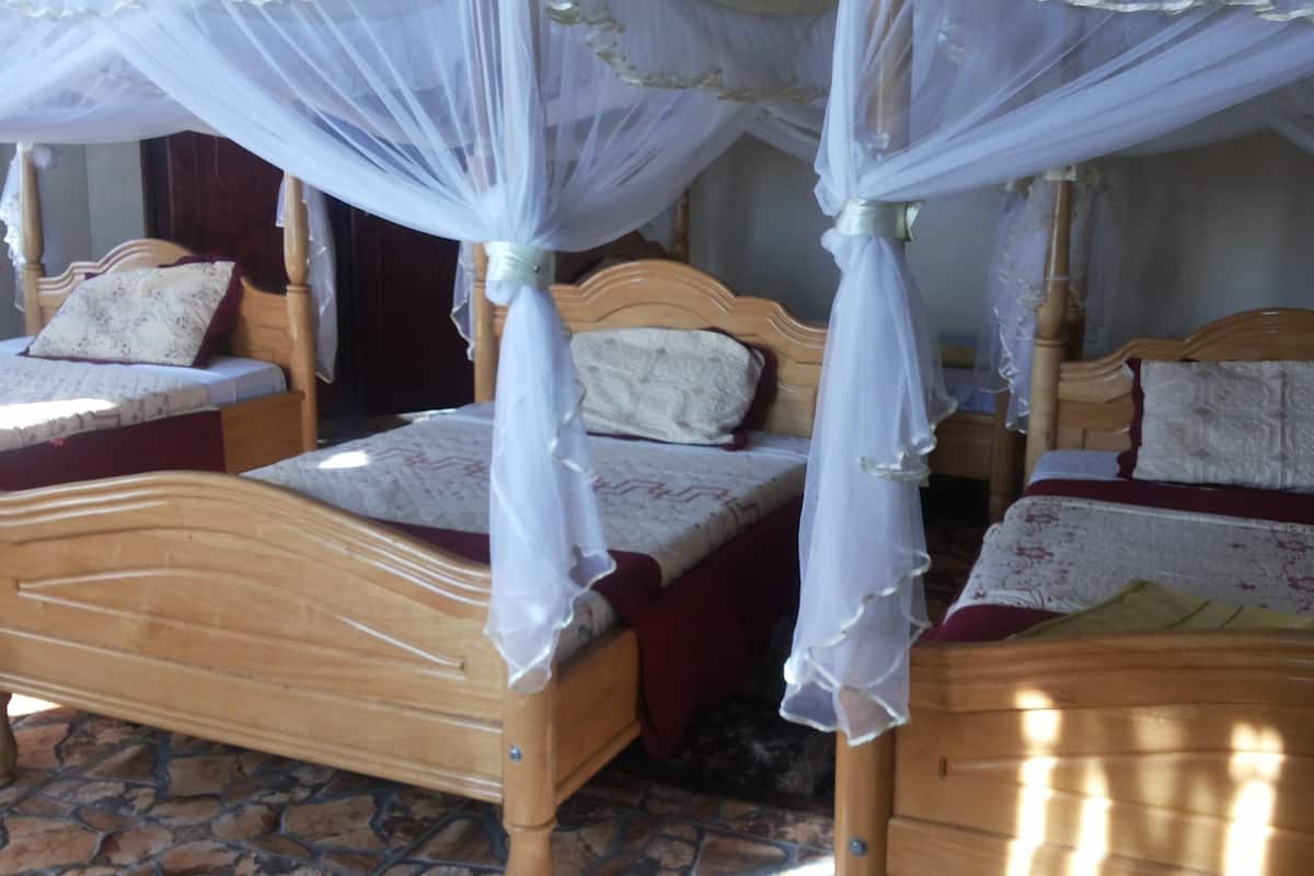 A room with two wooden beds, each with a canopy bedspread and pillows.