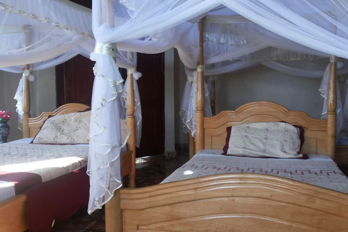 A room with four wooden beds, each with a canopy.