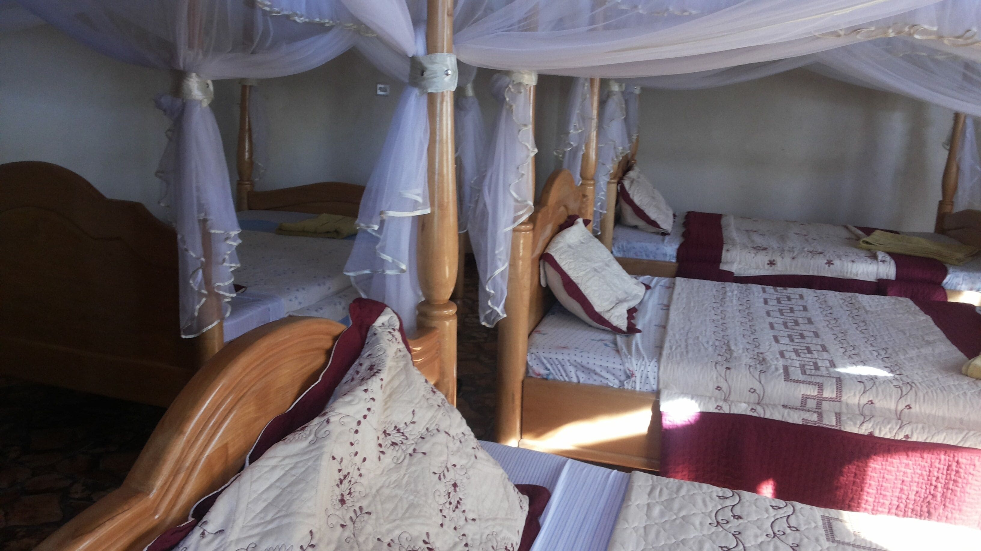 A room with two wooden beds, each with a canopy bedspread and pillows.