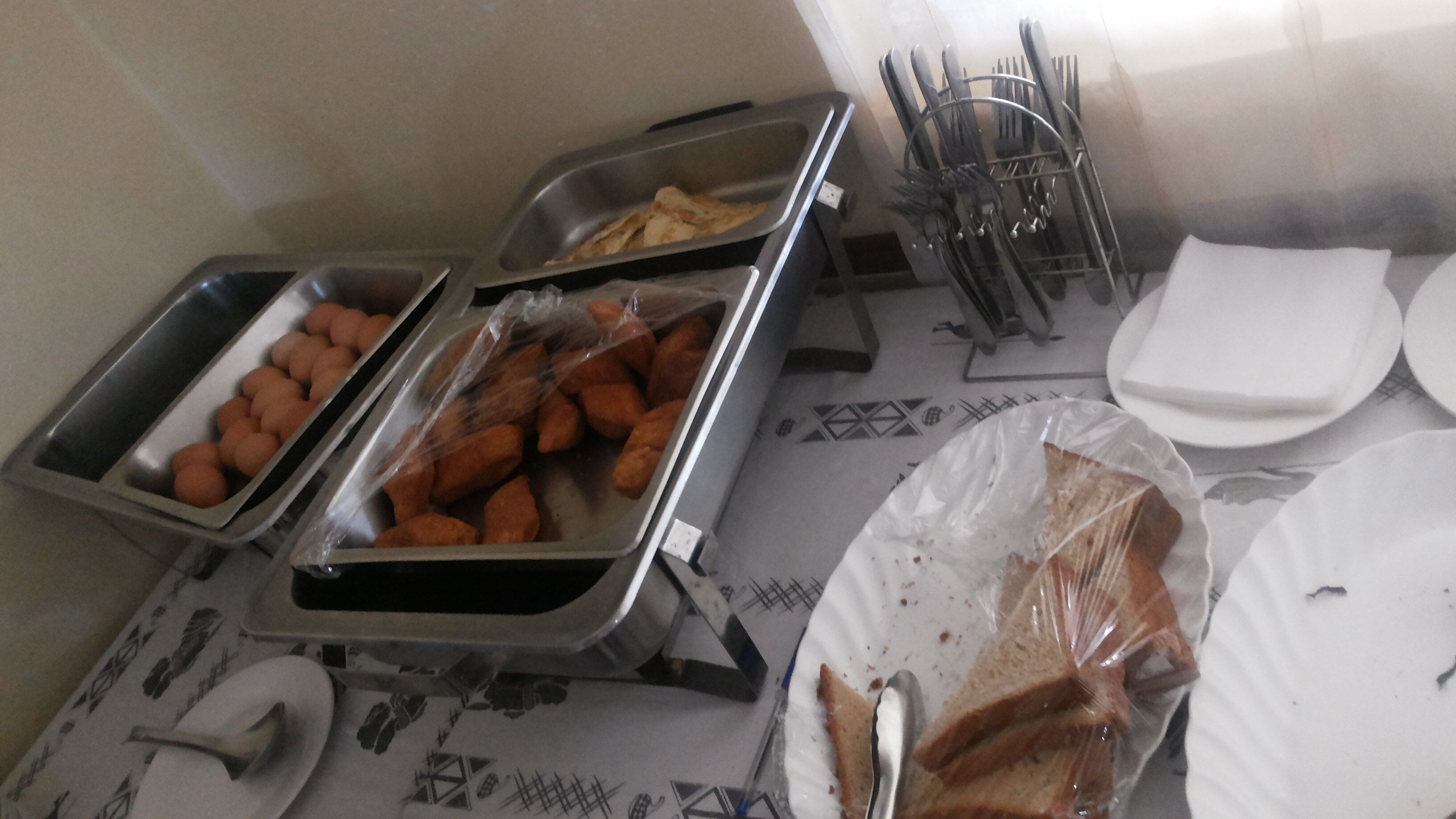 Un buffet con vassoi di cibo, un cesto di pane e un coltello.