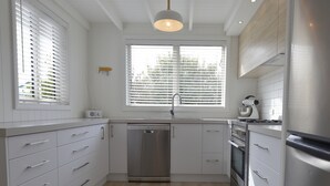 Een moderne keuken met witte kasten, een vaatwasser, een fornuis en een spoelbak.