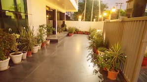 A pathway lined with potted plants leading to a building entrance. - Mavens White Artemis Hospital Road Gurgaon (Gurugram)