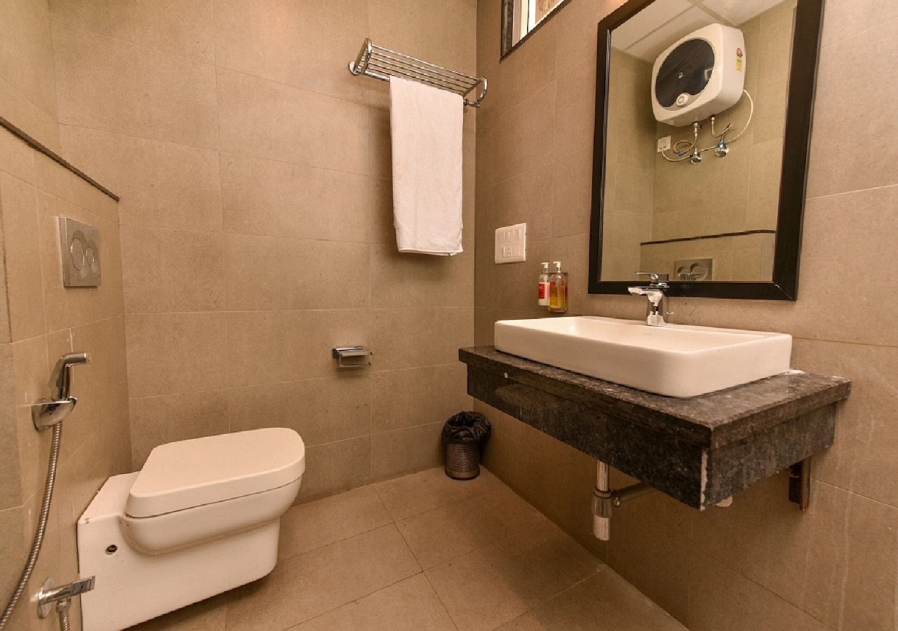 Een badkamer met toilet, wastafel, spiegel en handdoekhouder.
