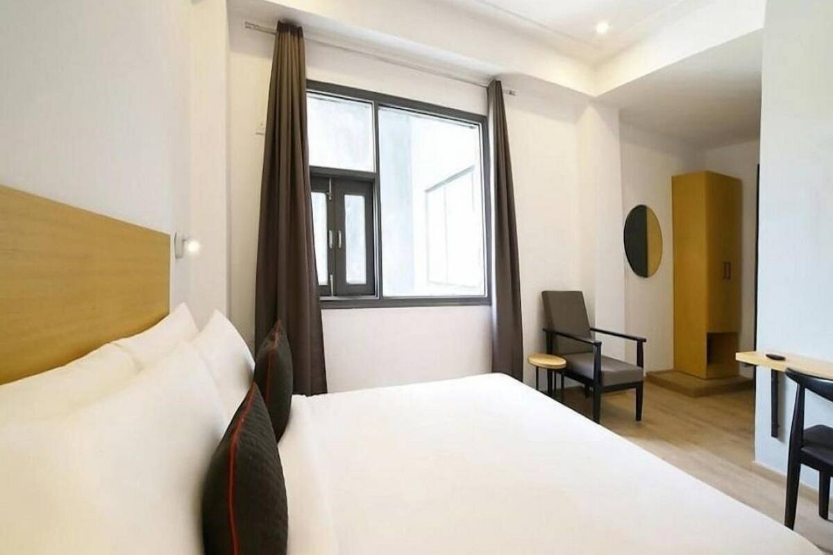 Una habitación de hotel con una cama grande, un escritorio, una silla y una ventana con cortinas.