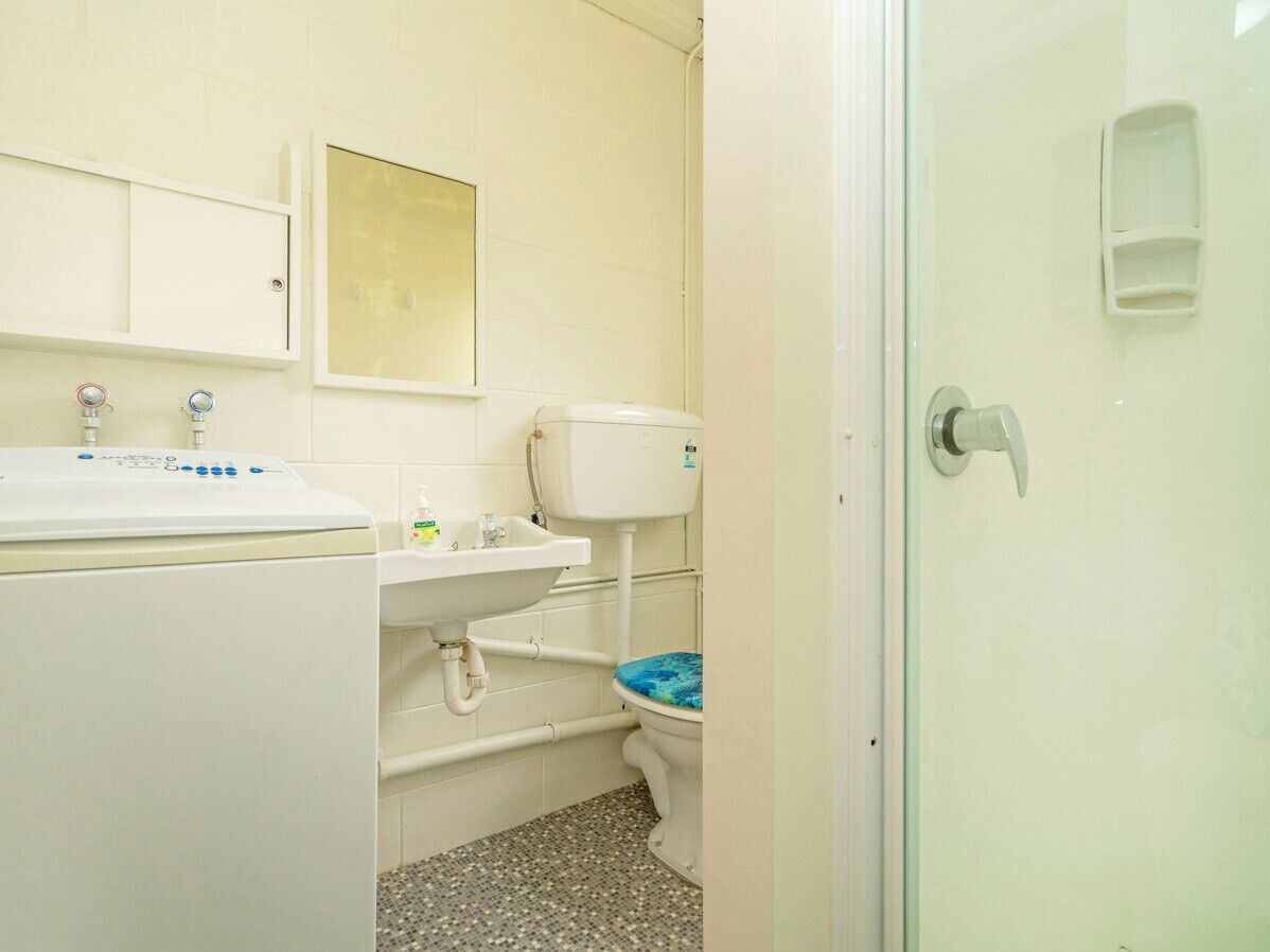 Une petite salle de bain avec des toilettes, un lavabo et un lave-linge.