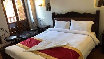 A neatly made bed with white and red bedding, a wooden headboard, and a small bedside table with a lamp.