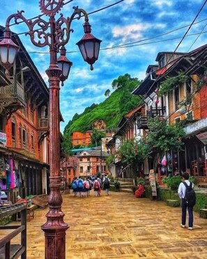 A narrow street with traditional buildings, a wooden floor, and a street lamp. - The Hotel Bandipur (Bandipur)