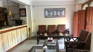 A reception area with a counter, seating, and a framed picture on the wall. - The Hotel Bandipur (Bandipur)