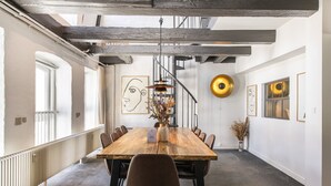 A spacious dining area with a long wooden table, multiple chairs, and a central vase with dried flowers. - The Churchill Penthouse by Daniel&Jacob’s (Copenhagen)