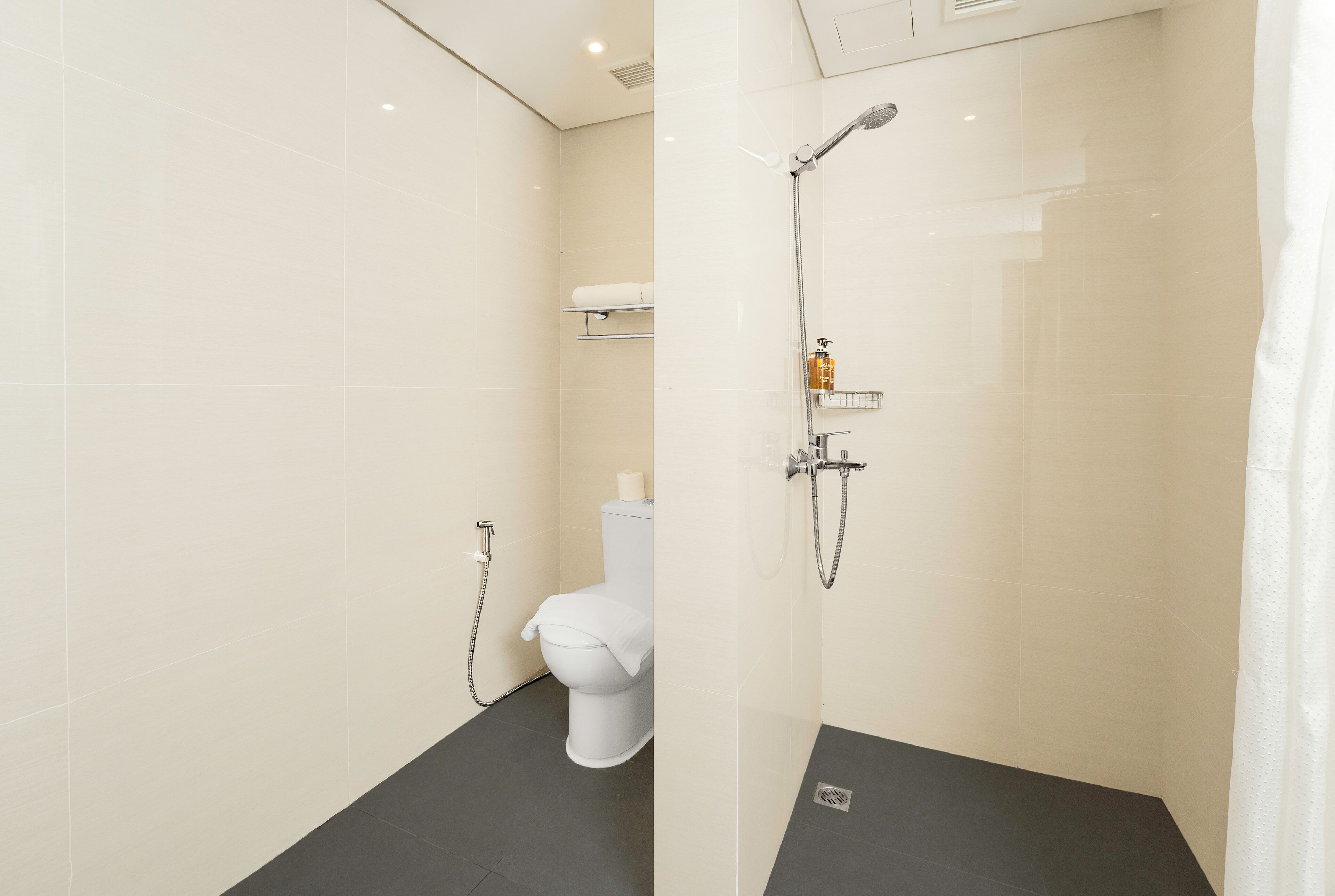 Un baño moderno con cabina de ducha de vidrio, inodoro y perchero.