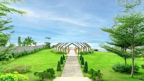 A pathway leading to a building with a unique architectural design, surrounded by well-maintained green lawns and trees.