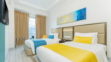 Habitación de hotel con dos camas, un televisor, un cuadro y una ventana con cortinas.