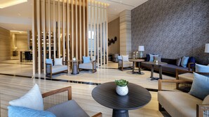 A modern lobby with a reception desk, seating area, and a patterned wall.