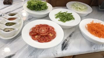 A kitchen counter with various vegetables and condiments.