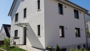 Ein zweistöckiges Gebäude mit flachem Dach, mehreren Fenstern und einer sichtbaren Tür.
