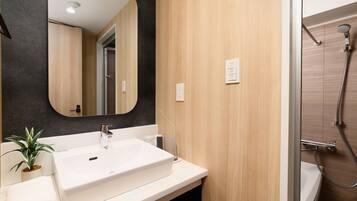 A modern bathroom with a white sink, a mirror, a shower, and wooden paneling.