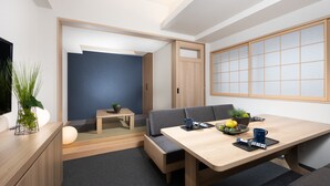A modern room with a wooden dining table, a sofa, and a small side table with a plant. - MIMARU Tokyo Shinjuku West (Tokyo)