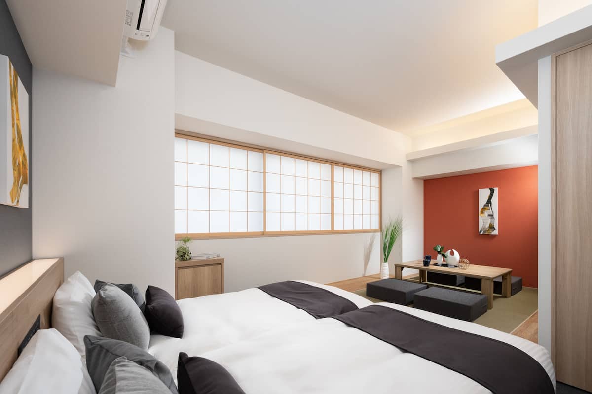 Ein modernes Hotelzimmer mit einem großen Bett, einem kleinen Schreibtisch, einem Fenster mit Aussicht und einer roten Akzentwand.