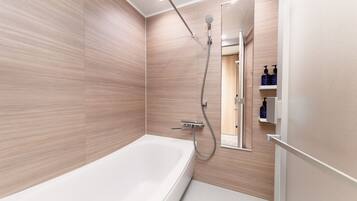 Un baño moderno con una bañera grande, una ducha con cabezal de ducha manual y un espejo.